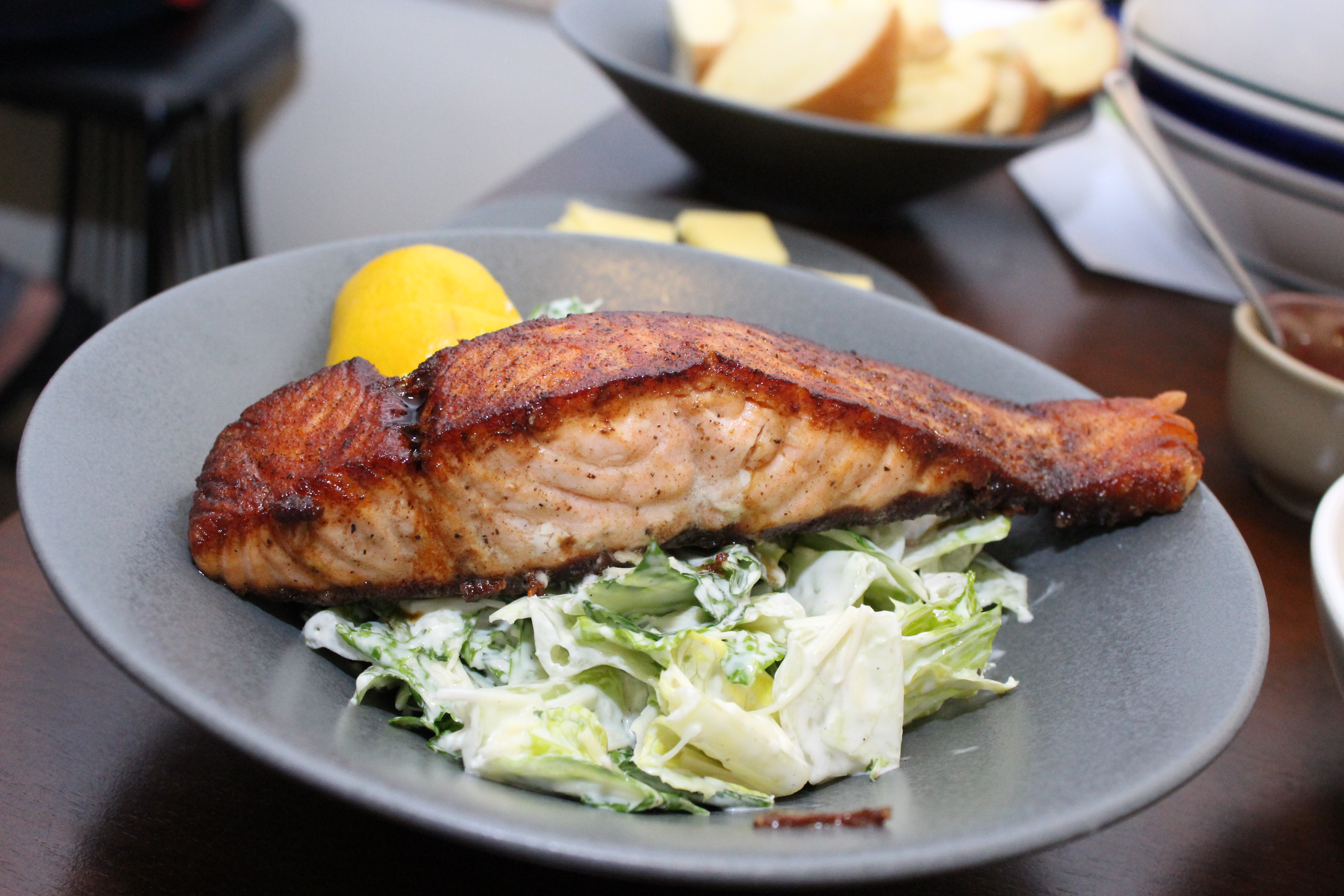 Pan-seared salmon over Caesar salad with a lemon wedge
